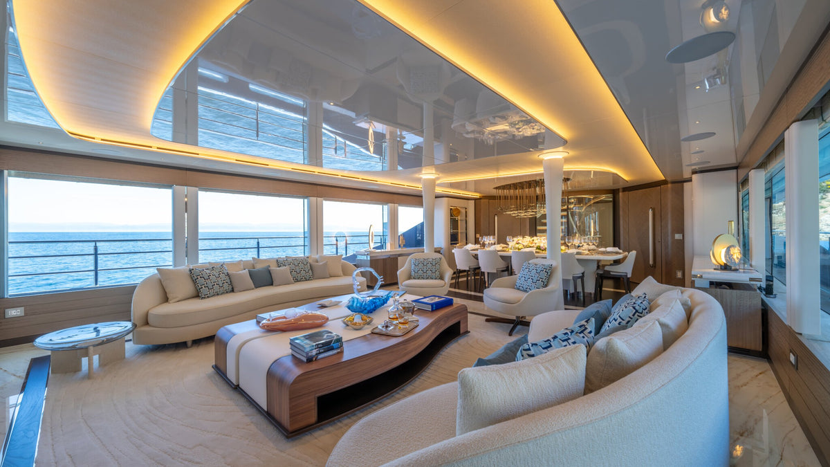 CAMILA main saloon seen from the dining end, curved sofas and walnut coffee table