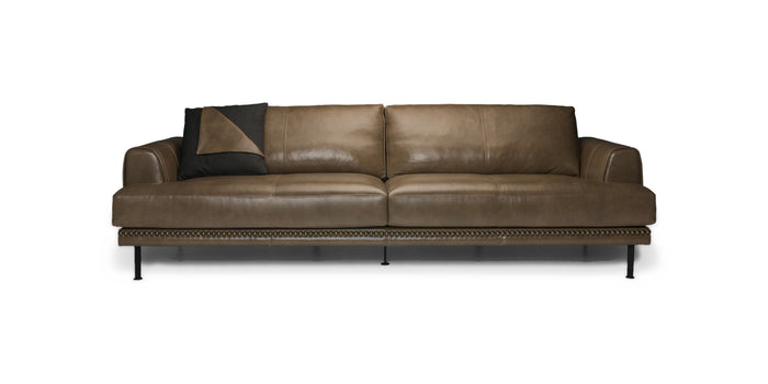 Divano Charlie in pelle marrone con borchie e cuscino decorativo, vista frontale