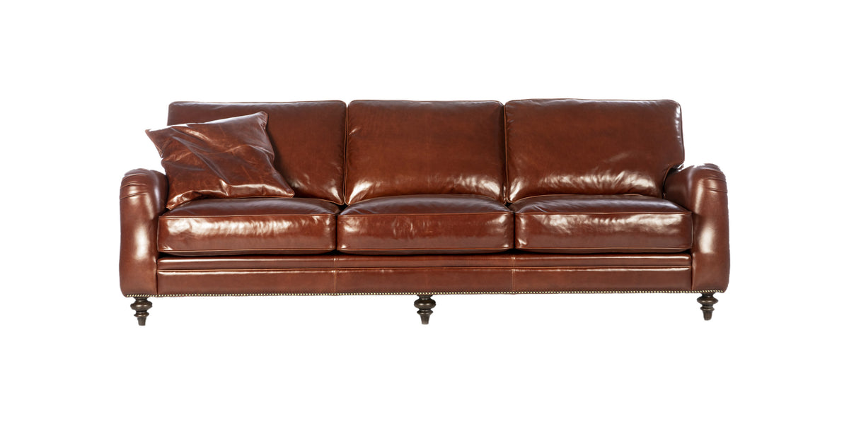 Divano Chelsea in pelle color cognac con tre cuscini di seduta e cuscino decorativo, vista frontale