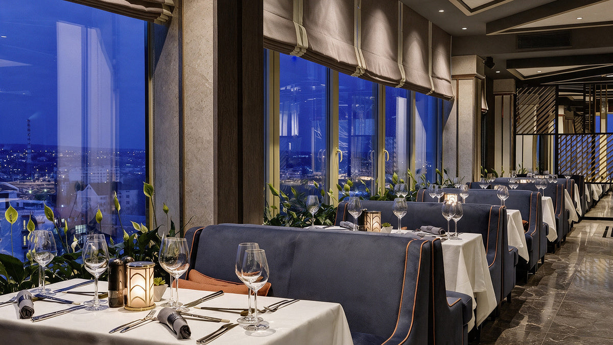 Navy velvet banquettes with contrast piping along the panoramic windows, Radisson Blu Leogrand, Chișinău