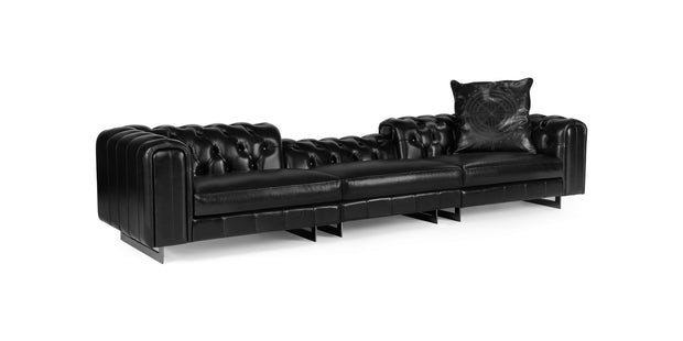 Windsor sofa in black leather with tufted back and channel-stitched arms on metal sled legs, three-quarter view
