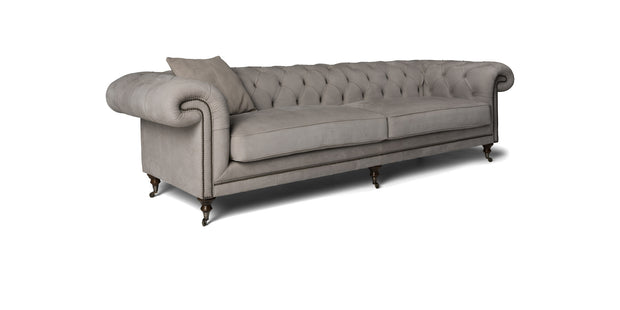 Divano Cambridge grigio chiaro con schienale capitonné, borchie e cuscino decorativo, vista di tre quarti