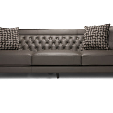 Divano Charlotte in pelle grigio scuro con schienale capitonné e cuscini decorativi, vista frontale