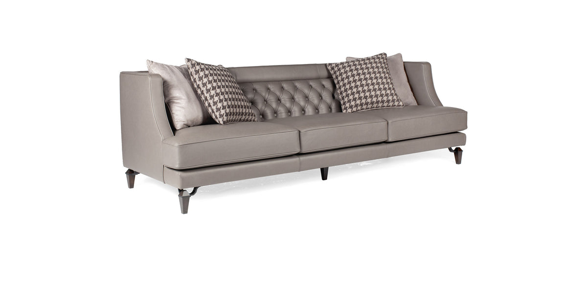 Divano Charlotte in pelle grigio chiaro con schienale capitonné e cuscini decorativi, vista di tre quarti