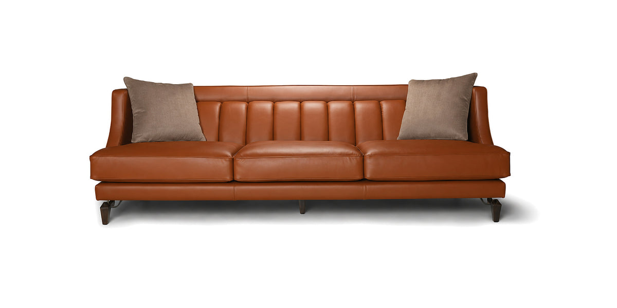 Divano Charlotte in pelle color cognac con schienale a cuciture verticali e cuscini decorativi, vista frontale