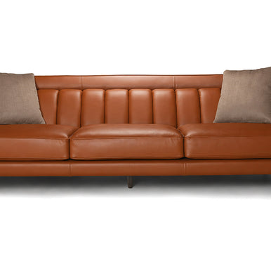 Divano Charlotte in pelle color cognac con schienale a cuciture verticali e cuscini decorativi, vista frontale