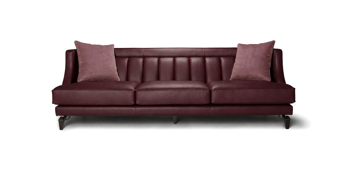 Divano Charlotte in pelle bordeaux con schienale a cuciture verticali e cuscini decorativi, vista frontale