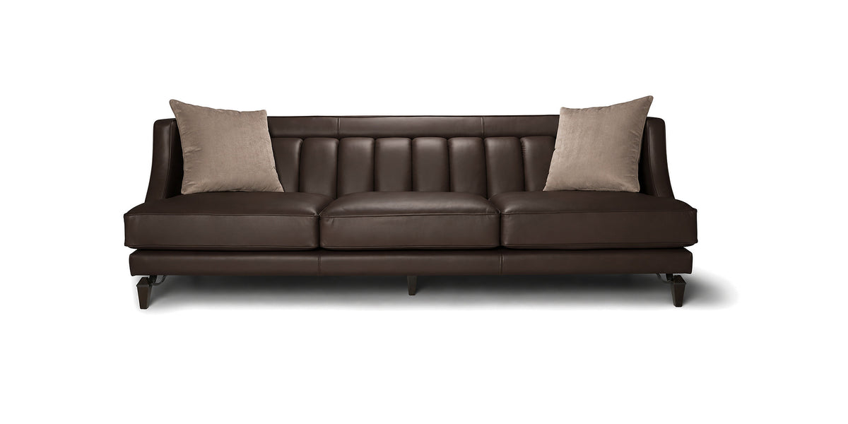 Divano Charlotte in pelle marrone scuro con schienale a cuciture verticali e cuscini decorativi, vista frontale
