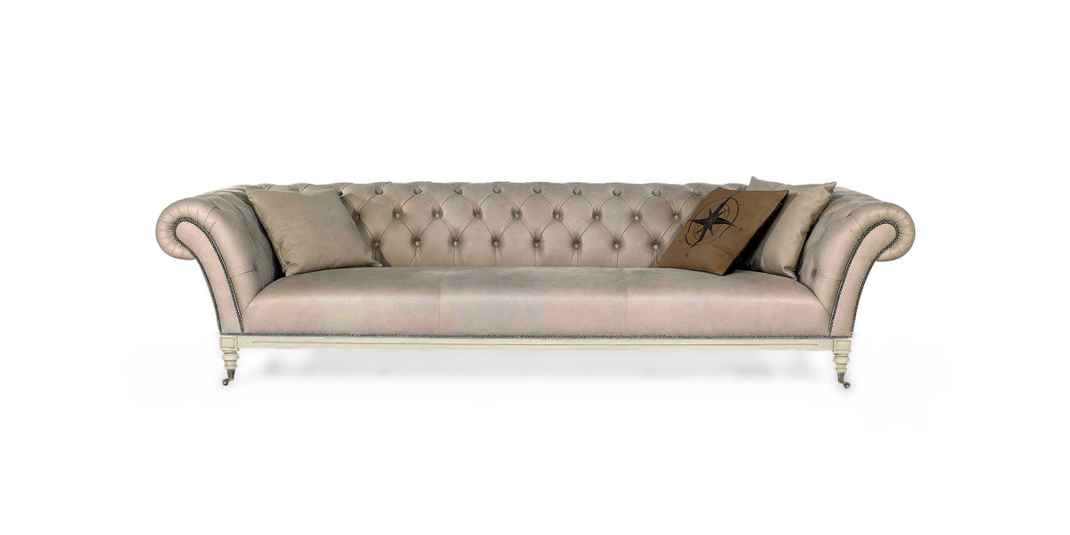 Divano Chesterfield Nottingham in pelle crema con schienale capitonné, cuscini decorativi e gambe tornite con ruote, vista frontale