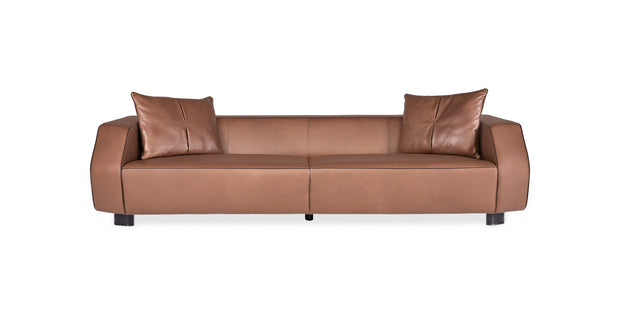 Divano Nova in pelle color cuoio con braccioli arrotondati e due cuscini decorativi, vista frontale