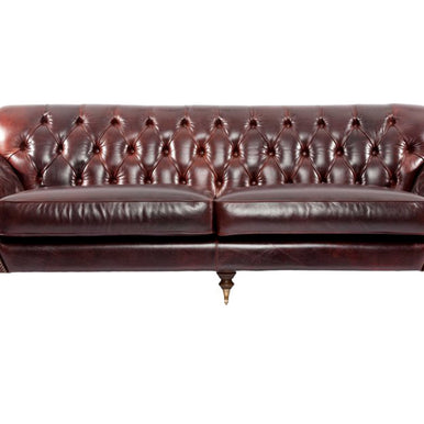 Диван Ramses в стиле Chesterfield из бордовой кожи со спинкой с каретной стяжкой, закруглёнными подлокотниками и точёными ножками на колёсиках, вид спереди
